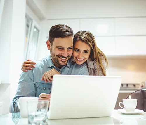 Smiling man and woman looking at a laptop together