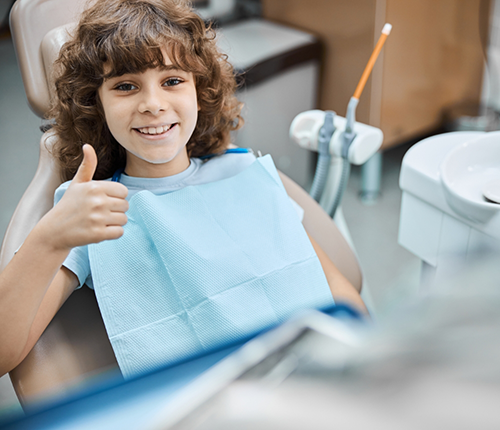 Child giving a thumbs up in the dental chair