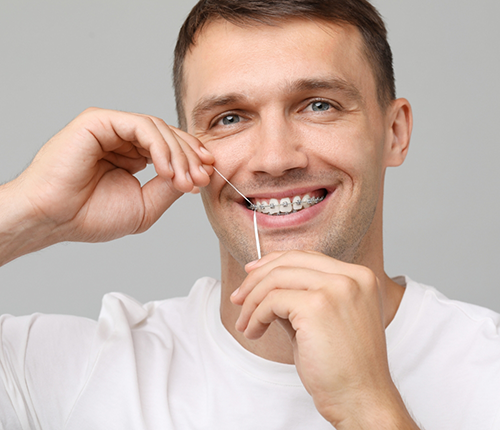 Man with braces flossing his teeth