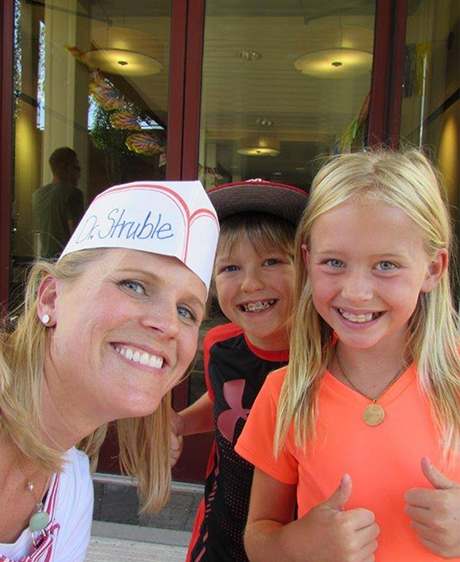Doctor Struble smiling with two kids with braces giving thumbs up