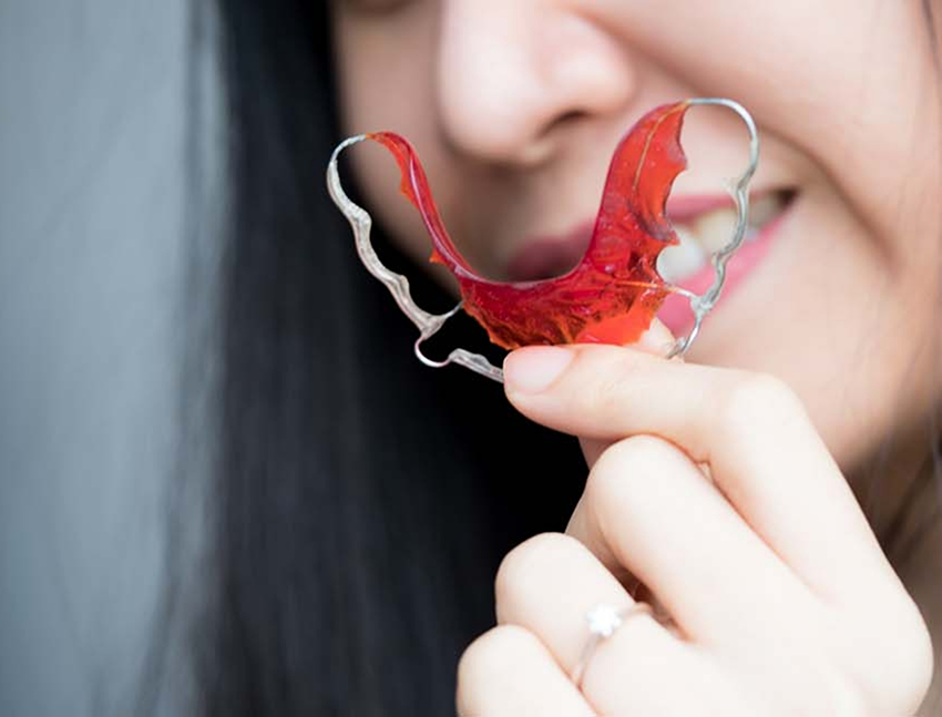 Person holding an orthodontic retainer in Bend