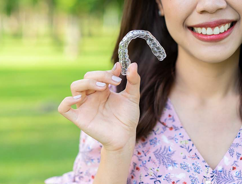 Smiling woman holding a Spark clear aligner in Bend