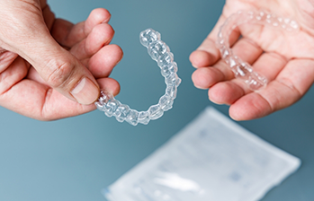 Person holding one clear aligner in each hand