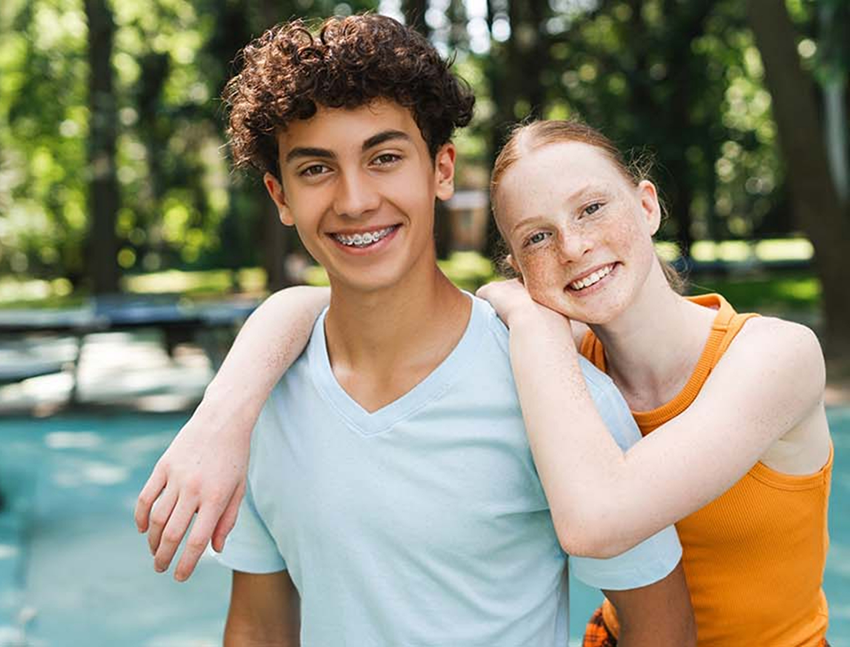 Two teenagers smiling with orthodontic appliances in Bend