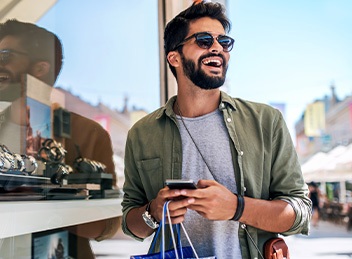 Smiling man shopping outside on sunny day