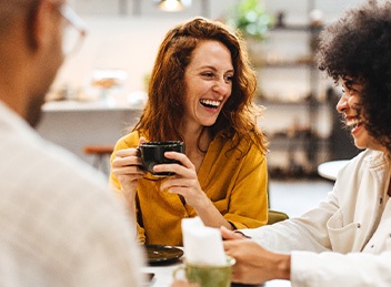 Group of friends smiling while enjoying cup of coffee