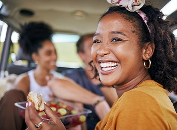 Woman smiling while eating snack on road trip