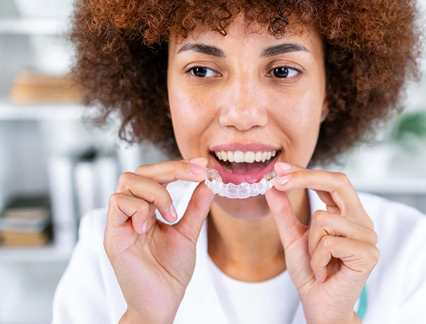 Person placing a clear aligner in Bend over their teeth