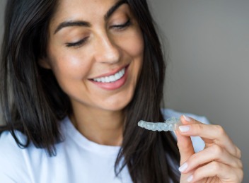 Smiling woman looking at her clear aligner